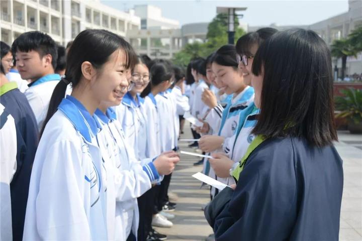 高二学生为对应班级的学姐学长系上了象征幸运的红丝带.