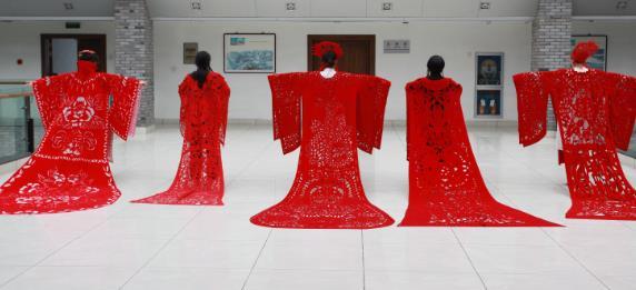 永康图书馆二楼大厅上演了一场别样时装秀,演员们穿上大红剪纸服装,若